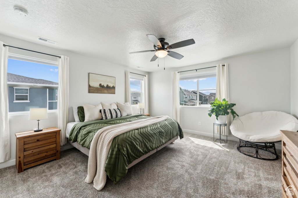 Bedroom with carpet floors, a textured ceiling, ceiling fan, and visible vents