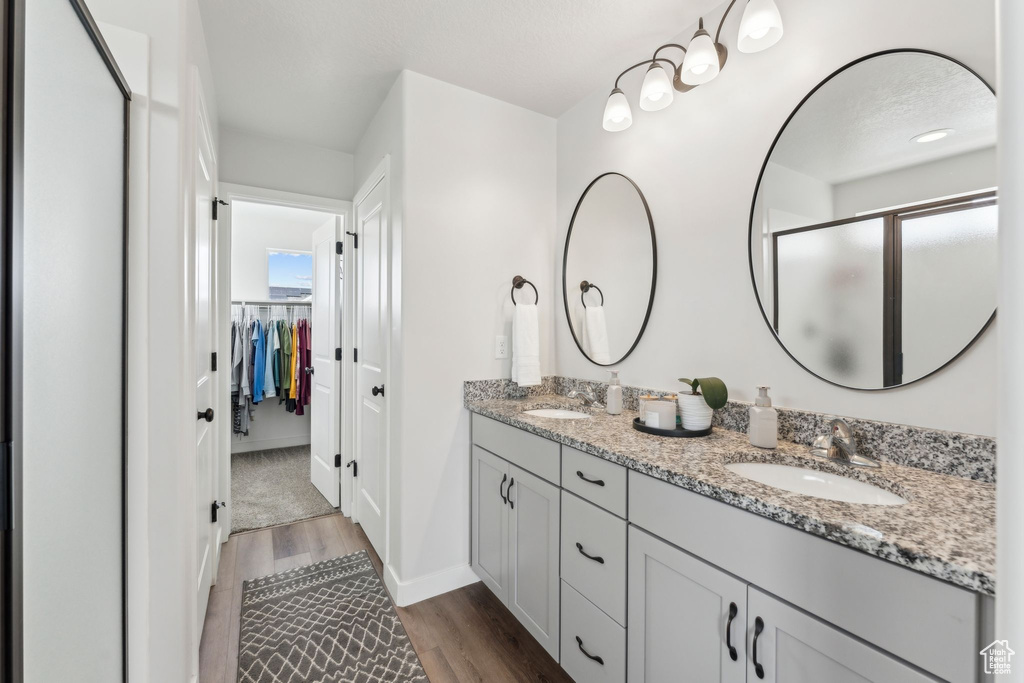 Bathroom with wood finished floors, double vanity, a sink, and a stall shower
