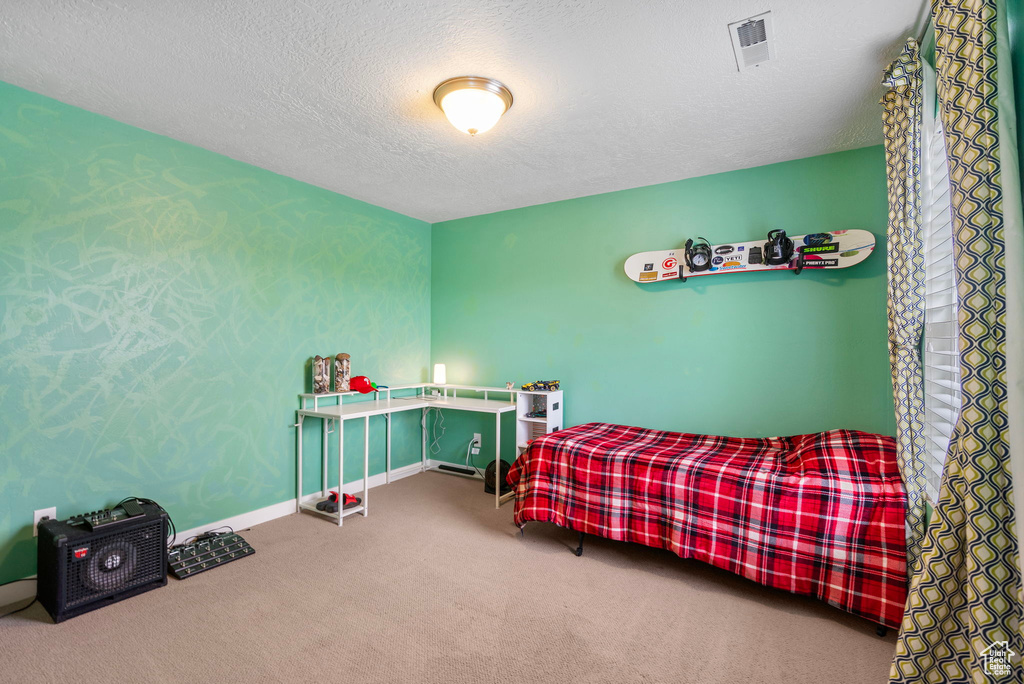 Carpeted bedroom featuring a textured ceiling, visible vents, and baseboards