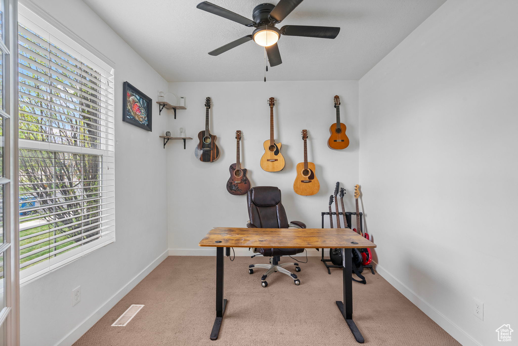 Carpeted home office featuring baseboards, a ceiling fan, and visible vents