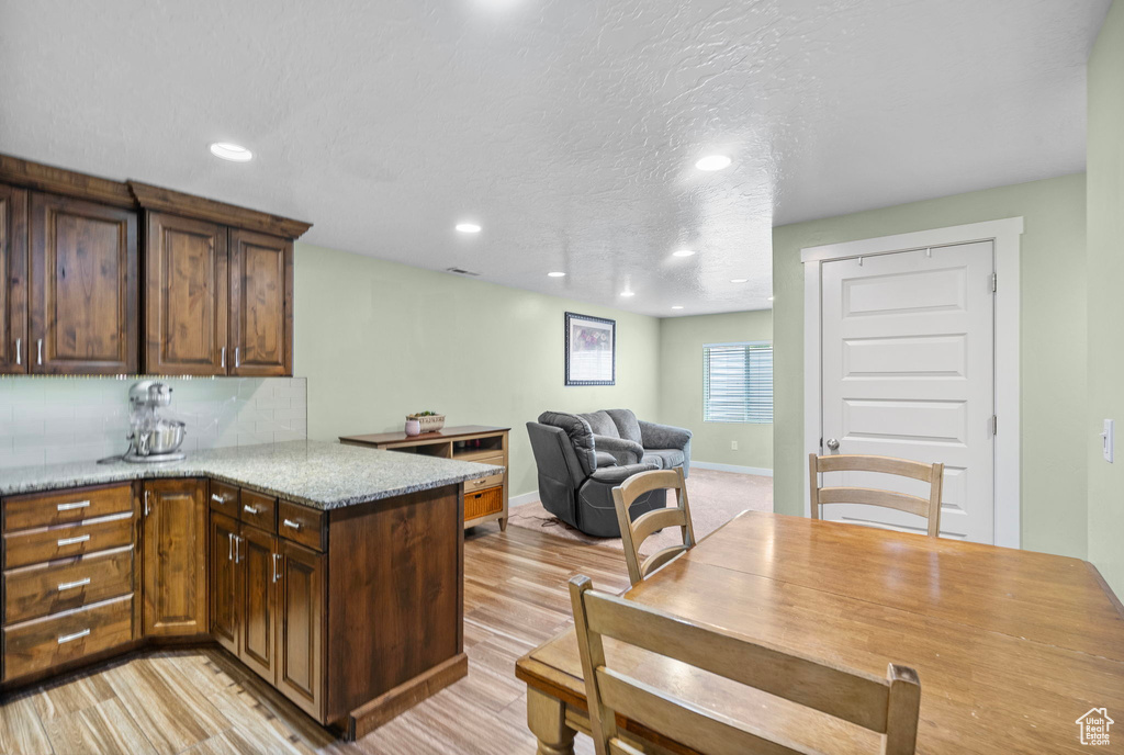 Kitchen with backsplash, a peninsula, recessed lighting, and light wood-type flooring