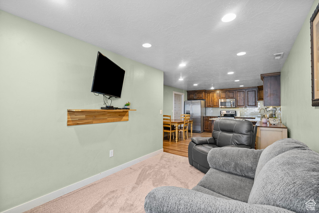 Living room featuring recessed lighting, baseboards, and light colored carpet