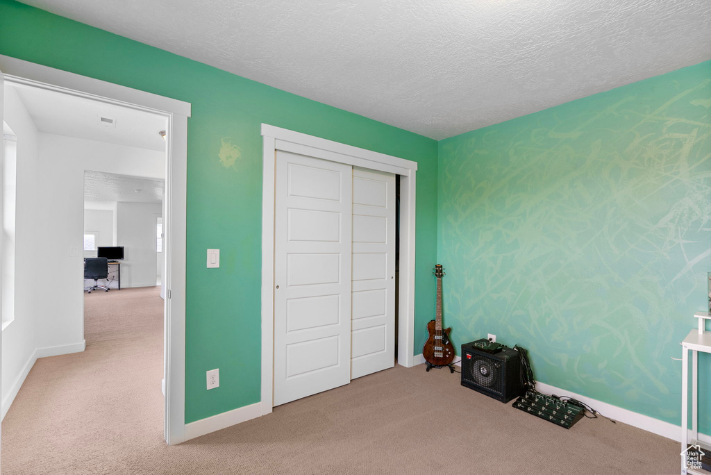 Unfurnished bedroom featuring a closet, baseboards, carpet flooring, and a textured ceiling