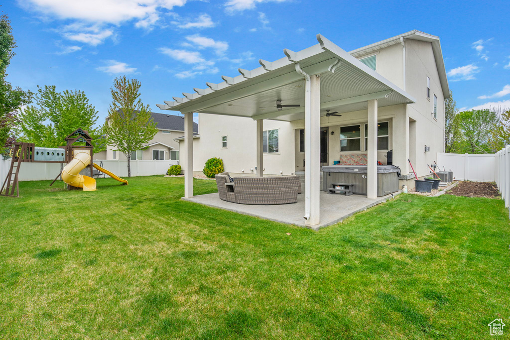 Back of property featuring a hot tub, stucco siding, a fenced backyard, a patio area, and a ceiling fan
