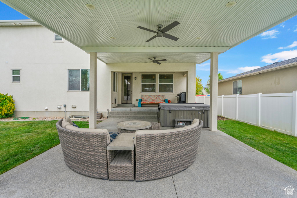 View of patio featuring fence, outdoor dining area, ceiling fan, and a hot tub