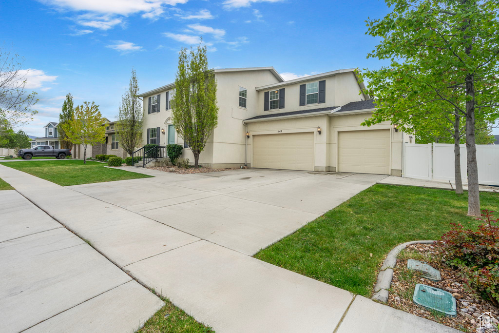 View of front of home with fence, a front lawn, concrete driveway, an attached garage, and stucco siding