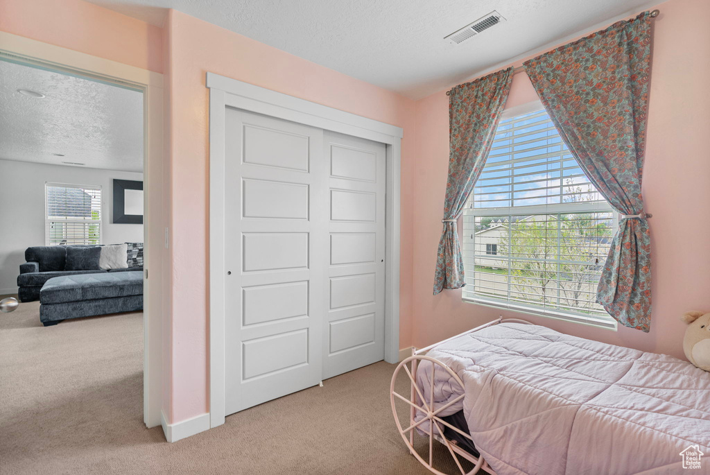 Bedroom featuring a textured ceiling, visible vents, light carpet, and baseboards