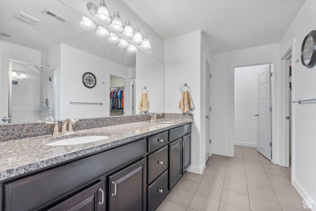 Full bathroom featuring visible vents, a sink, a stall shower, and double vanity