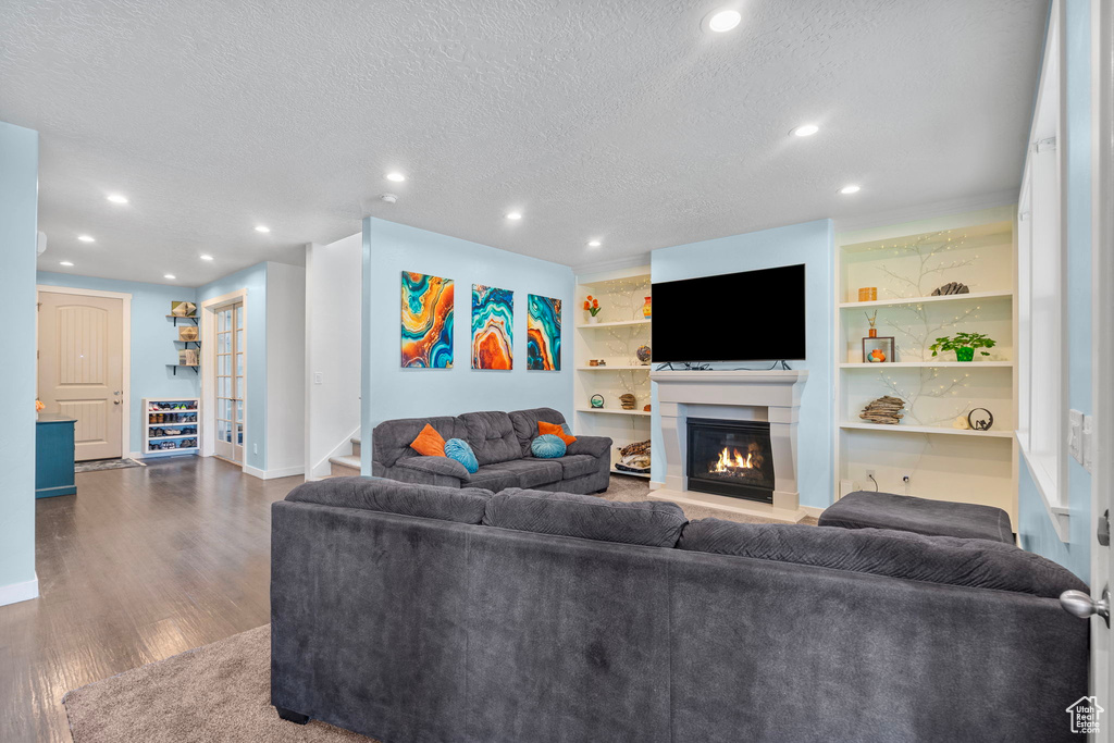 Living area featuring recessed lighting, a textured ceiling, dark wood-style flooring, and a glass covered fireplace
