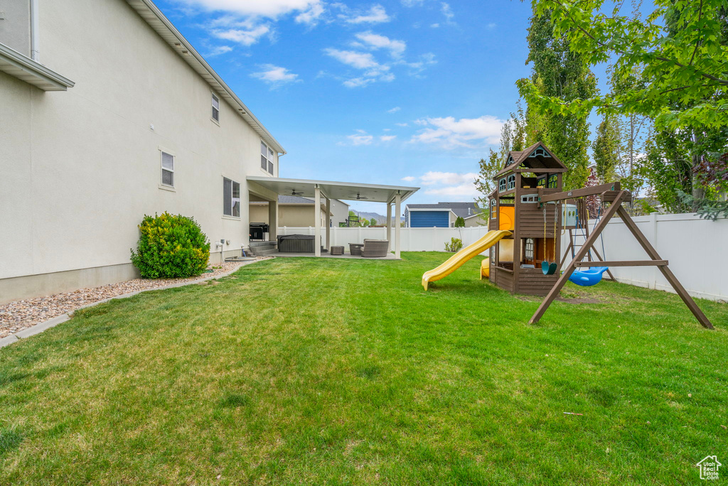 View of yard with a patio, a jacuzzi, a fenced backyard, and a playground