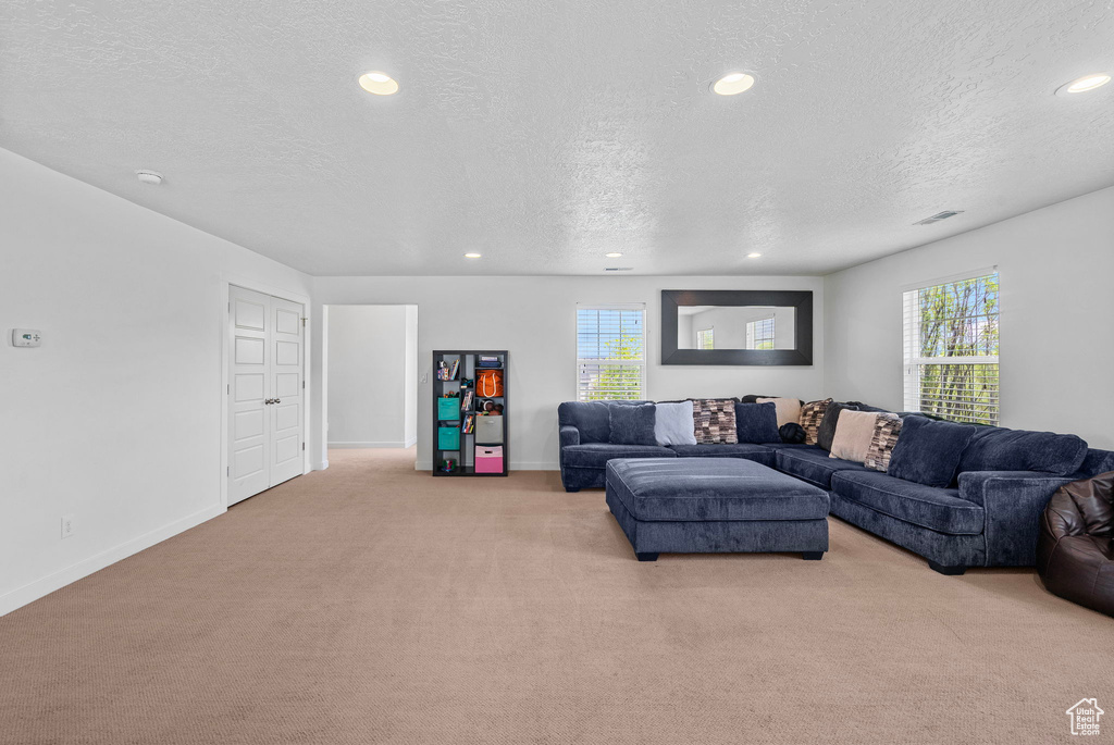 Living area featuring baseboards, light carpet, recessed lighting, and a textured ceiling