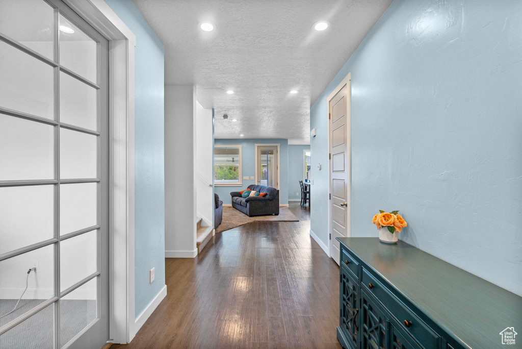 Hallway with recessed lighting, a textured ceiling, dark wood finished floors, and baseboards