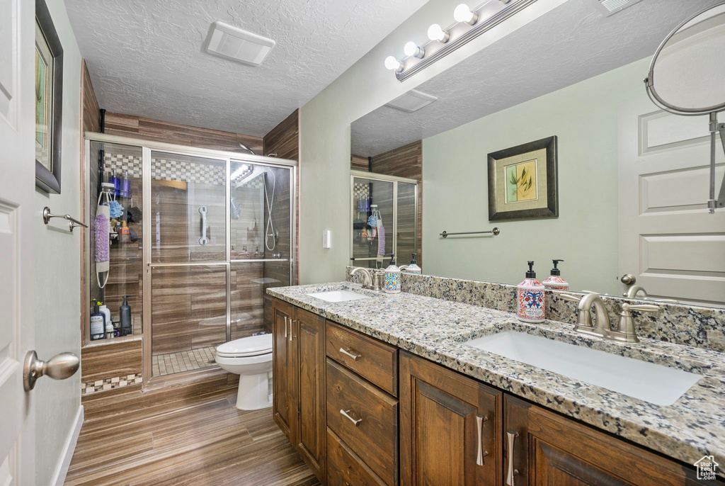 Bathroom featuring double vanity, a sink, a stall shower, and toilet