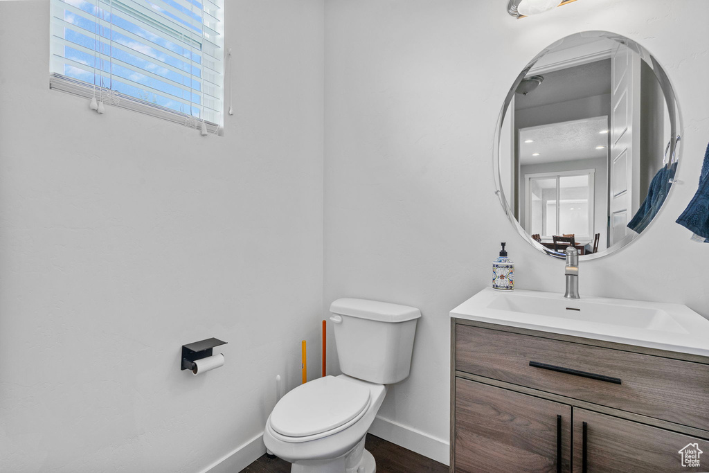 Bathroom featuring toilet, baseboards, wood finished floors, and vanity