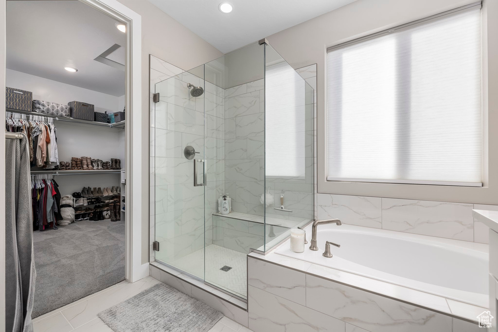 Bathroom featuring a healthy amount of sunlight, a marble finish shower, a bath, and a walk in closet