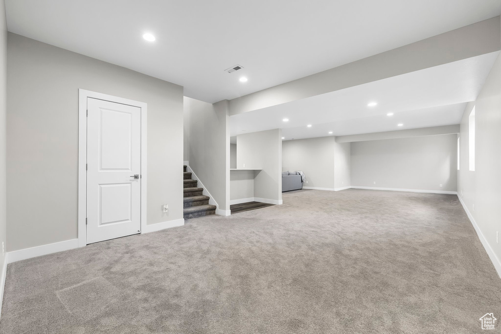Finished basement with visible vents, baseboards, stairway, recessed lighting, and carpet