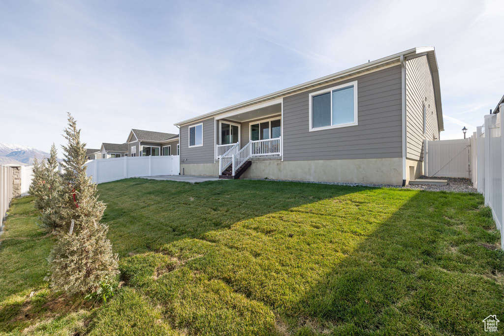 Back of house featuring a lawn, covered porch, and a fenced backyard