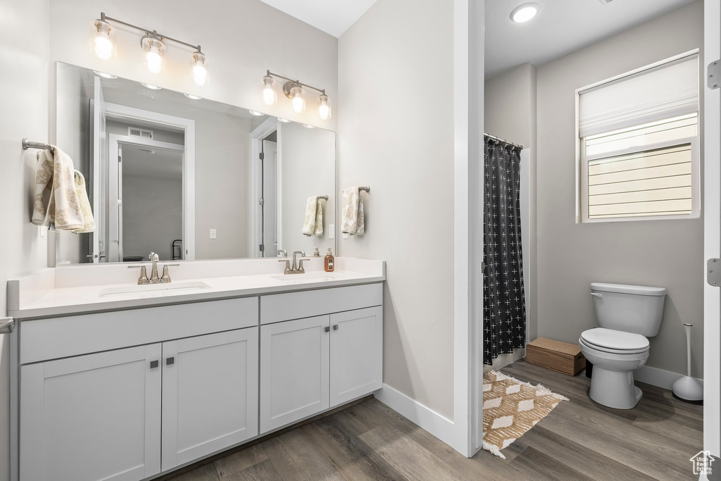 Bathroom featuring toilet, baseboards, a sink, and wood finished floors