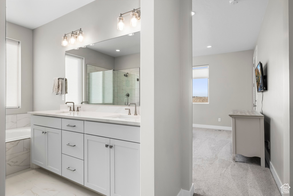 Bathroom featuring a sink, a bath, a stall shower, and double vanity