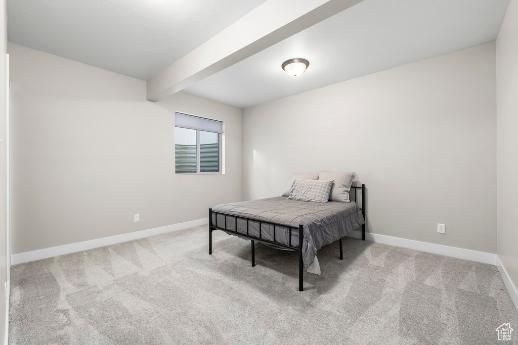 Carpeted bedroom with baseboards and beamed ceiling
