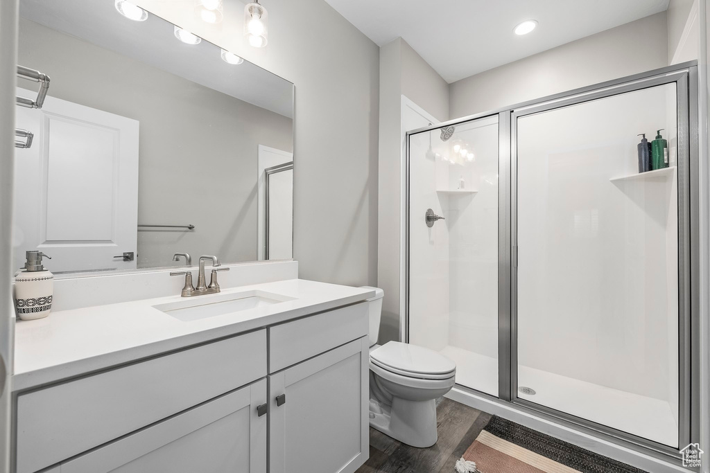 Bathroom featuring vanity, toilet, recessed lighting, wood finished floors, and a stall shower