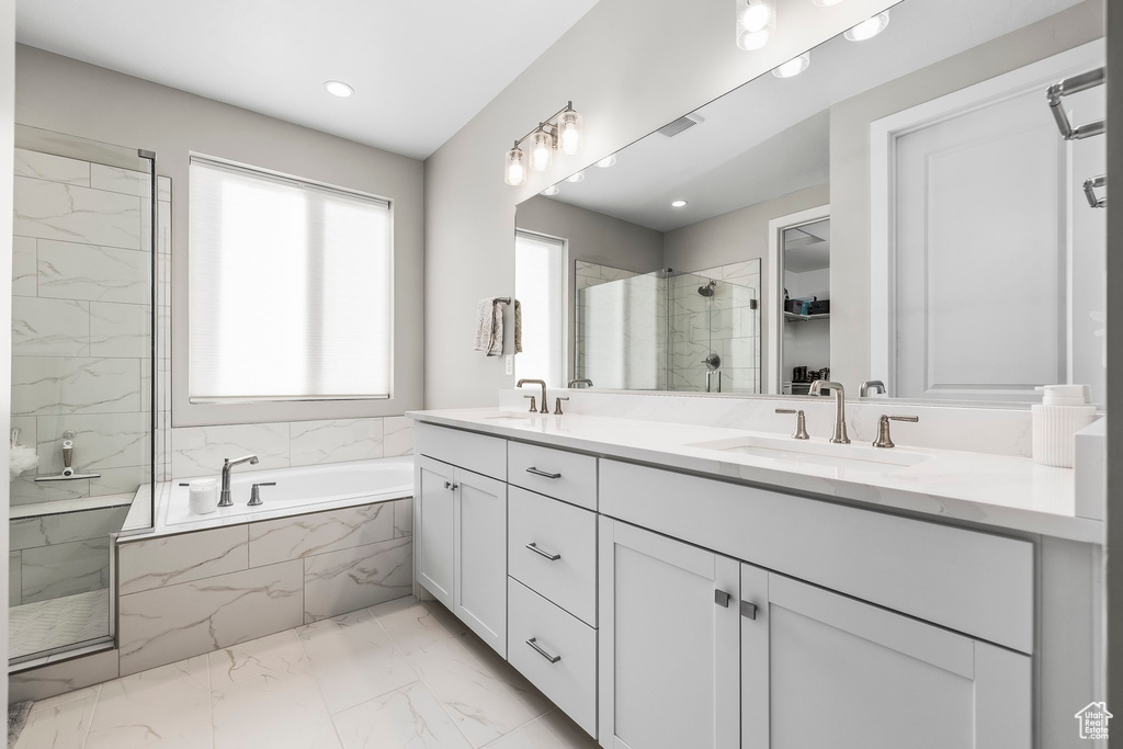 Bathroom featuring a garden tub, a sink, marble finish floor, and a shower stall
