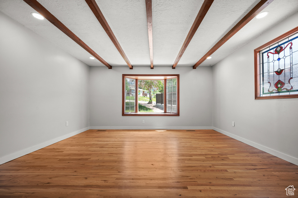 Unfurnished room with beam ceiling, recessed lighting, light wood-type flooring, and baseboards