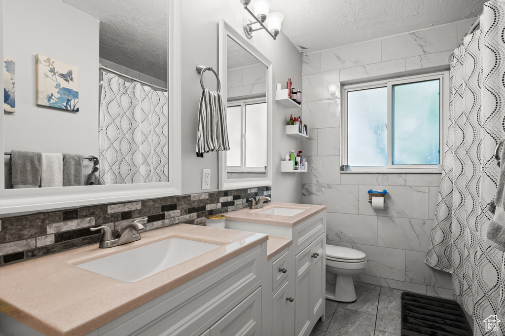 Bathroom with a sink, toilet, a textured ceiling, and marble finish floor