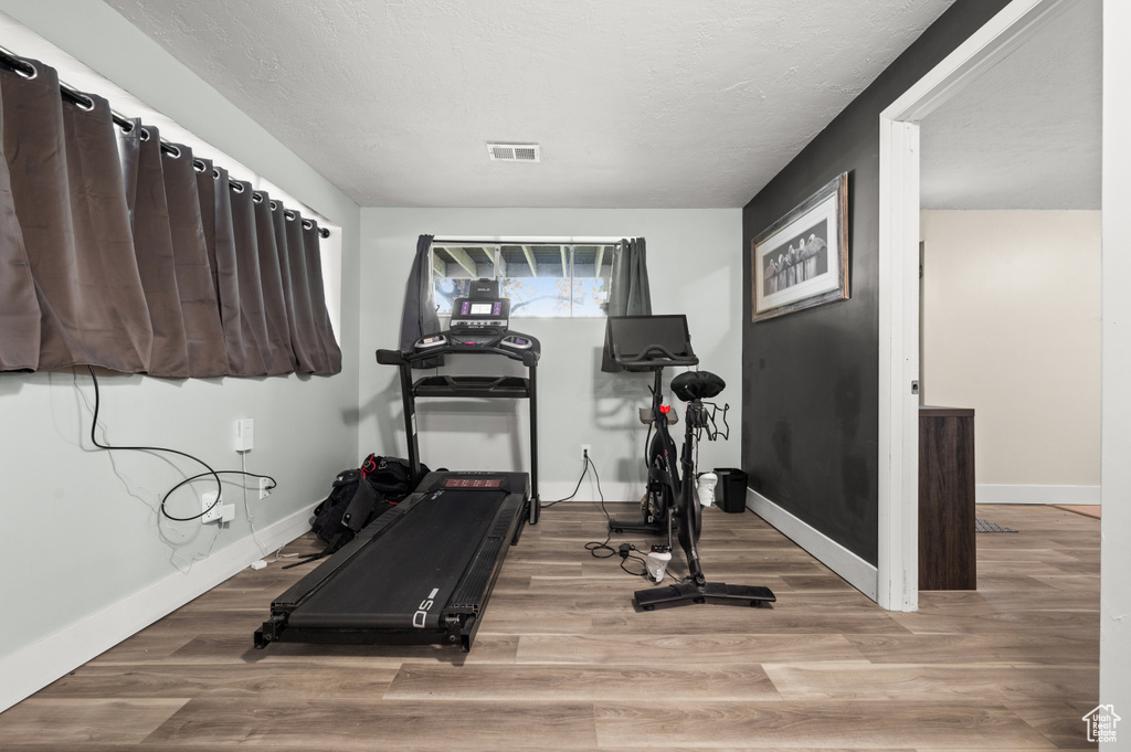 Workout area featuring visible vents, baseboards, and wood finished floors