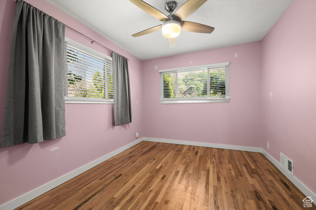 Unfurnished room with healthy amount of natural light, wood finished floors, and baseboards