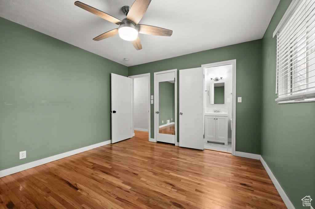 Unfurnished bedroom featuring baseboards, light wood-type flooring, connected bathroom, and ceiling fan