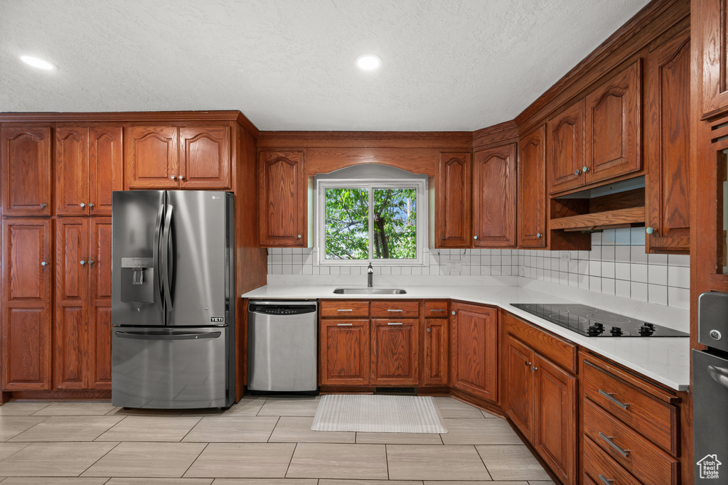 Kitchen featuring appliances with stainless steel finishes, a sink, backsplash, light countertops, and recessed lighting