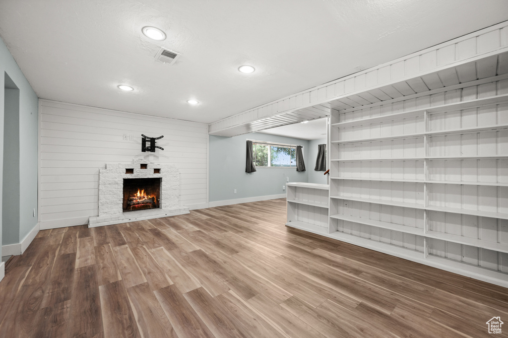 Unfurnished living room featuring baseboards, wood finished floors, a lit fireplace, and recessed lighting