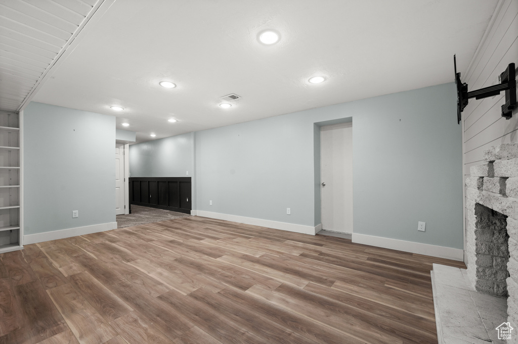 Unfurnished living room with wood finished floors, recessed lighting, a fireplace, baseboards, and a barn door