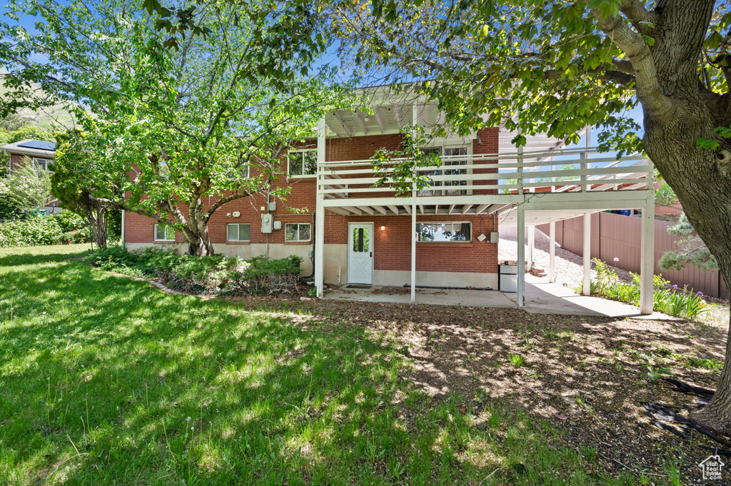 Back of property featuring brick siding, a patio, a lawn, and a deck