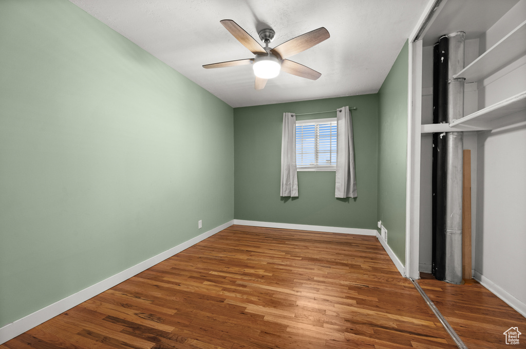 Unfurnished bedroom featuring wood finished floors, baseboards, a closet, and a ceiling fan