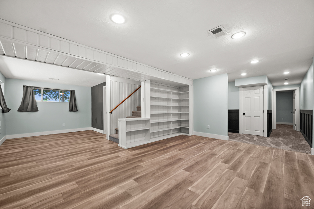 Basement with baseboards, wood finished floors, stairway, recessed lighting, and built in shelves