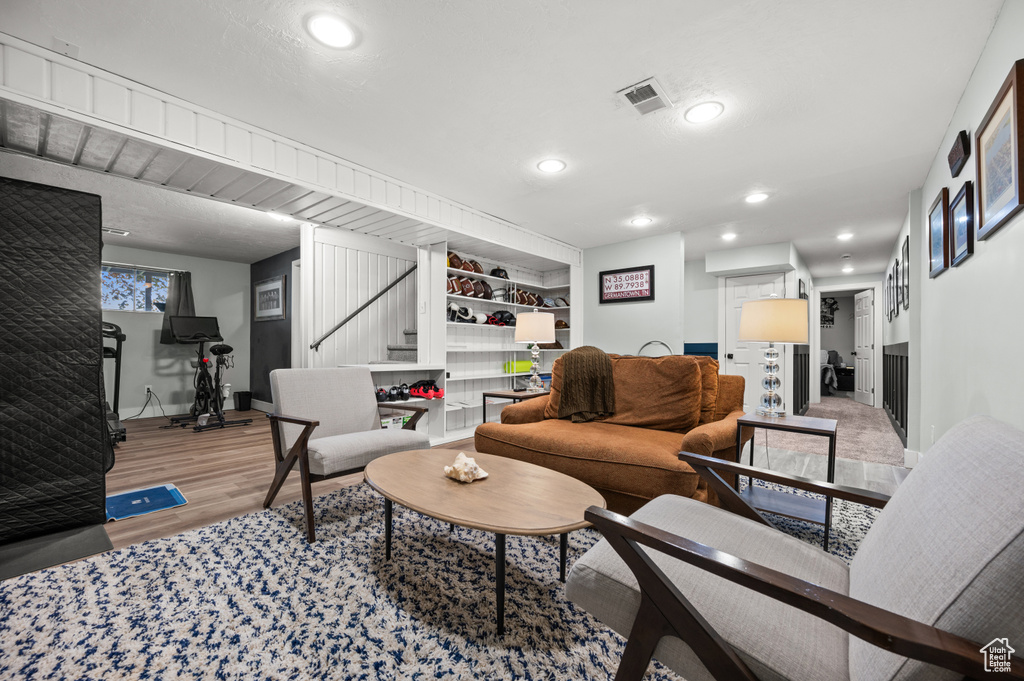 Living room with recessed lighting, baseboards, wood finished floors, visible vents, and stairway