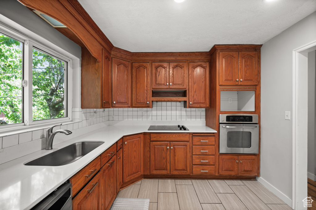 Kitchen with appliances with stainless steel finishes, a sink, tasteful backsplash, and light countertops