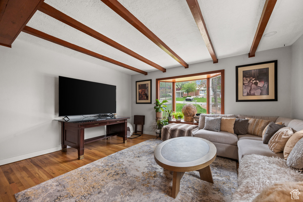 Living area with baseboards, beam ceiling, and wood finished floors