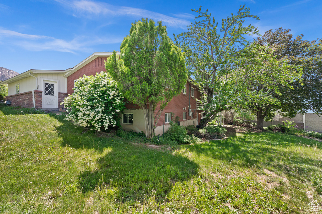 View of side of property with brick siding and a yard