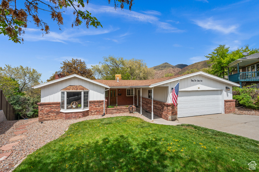 Ranch-style house featuring driveway, a chimney, a garage, brick siding, and a front lawn