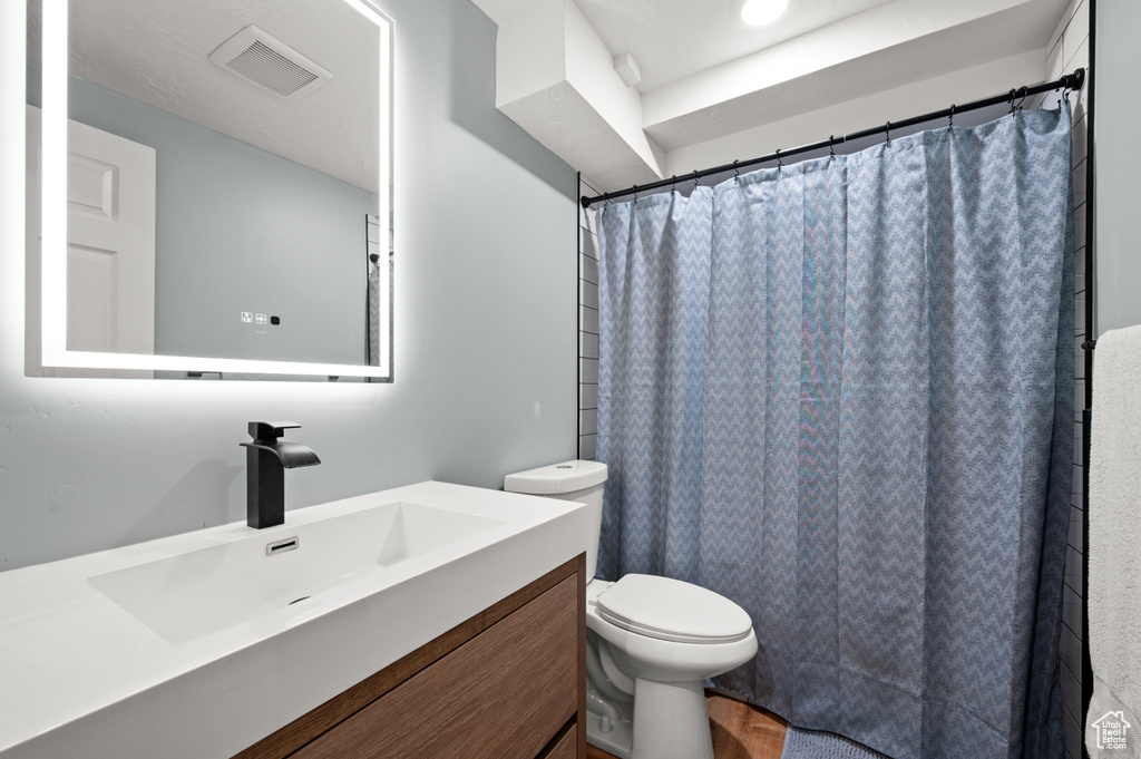 Bathroom with visible vents, a shower with shower curtain, toilet, and vanity