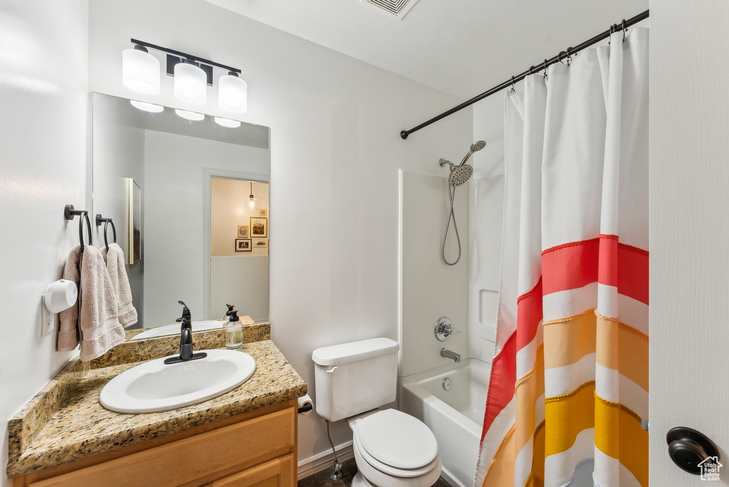 Full bathroom featuring vanity, shower / bath combo, and toilet