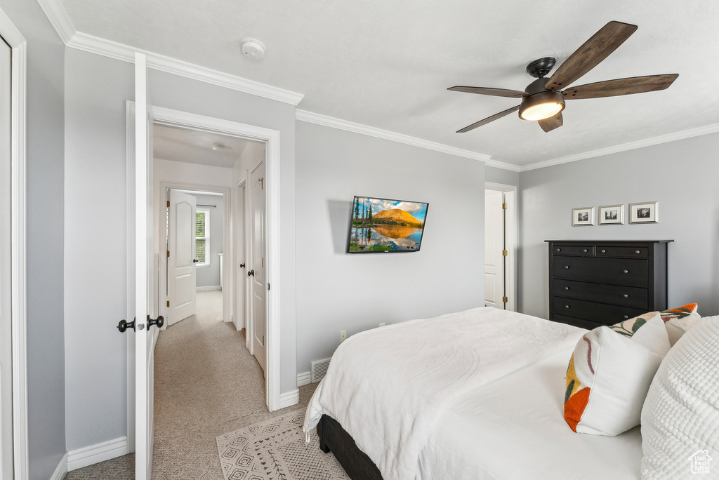Bedroom featuring crown molding, baseboards, ceiling fan, and light carpet