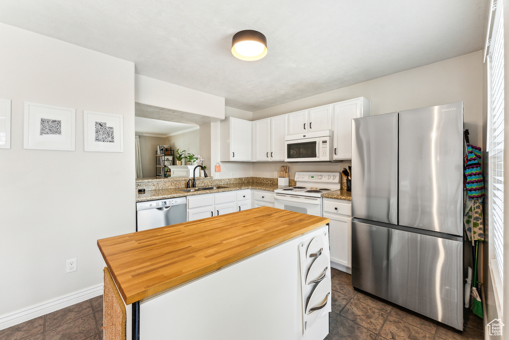 Kitchen with a sink, stainless steel appliances, butcher block countertops, and white cabinetry