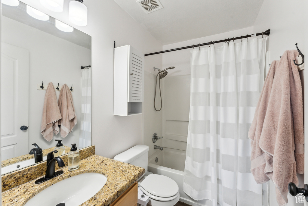 Full bath featuring visible vents, shower / bath combo with shower curtain, toilet, and vanity