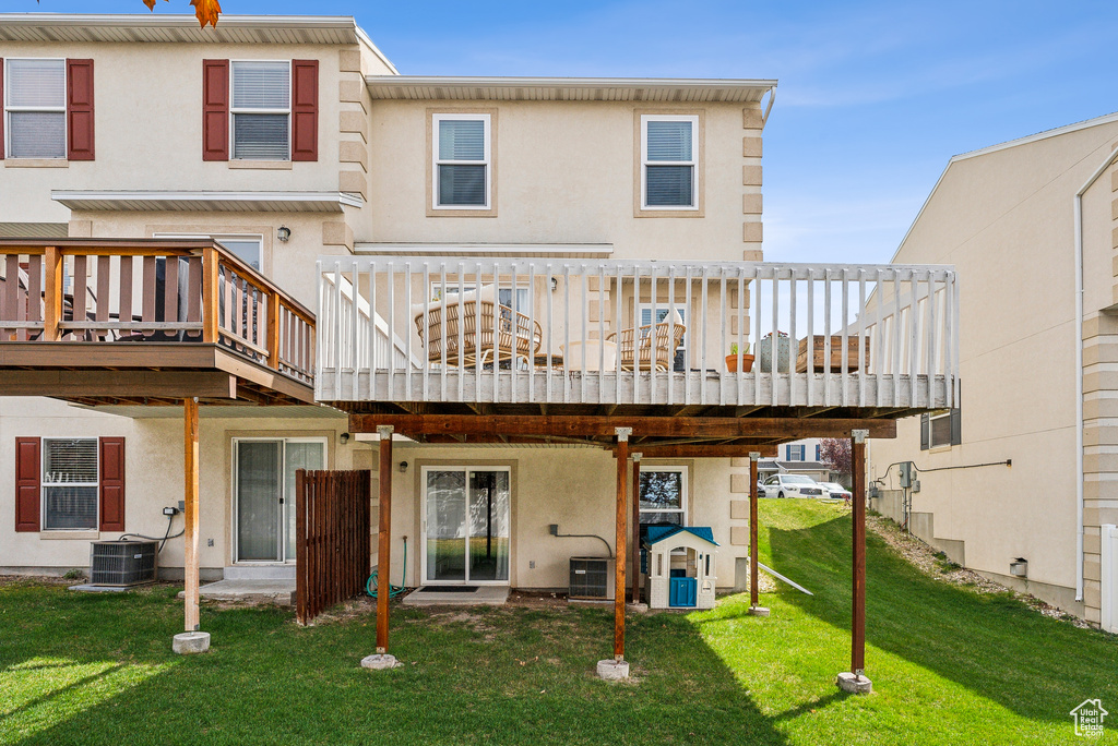 Back of property featuring a lawn, a wooden deck, and stucco siding