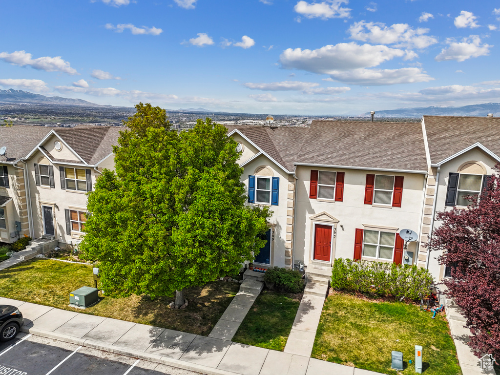 Multi unit property with uncovered parking, a shingled roof, a front yard, and stucco siding