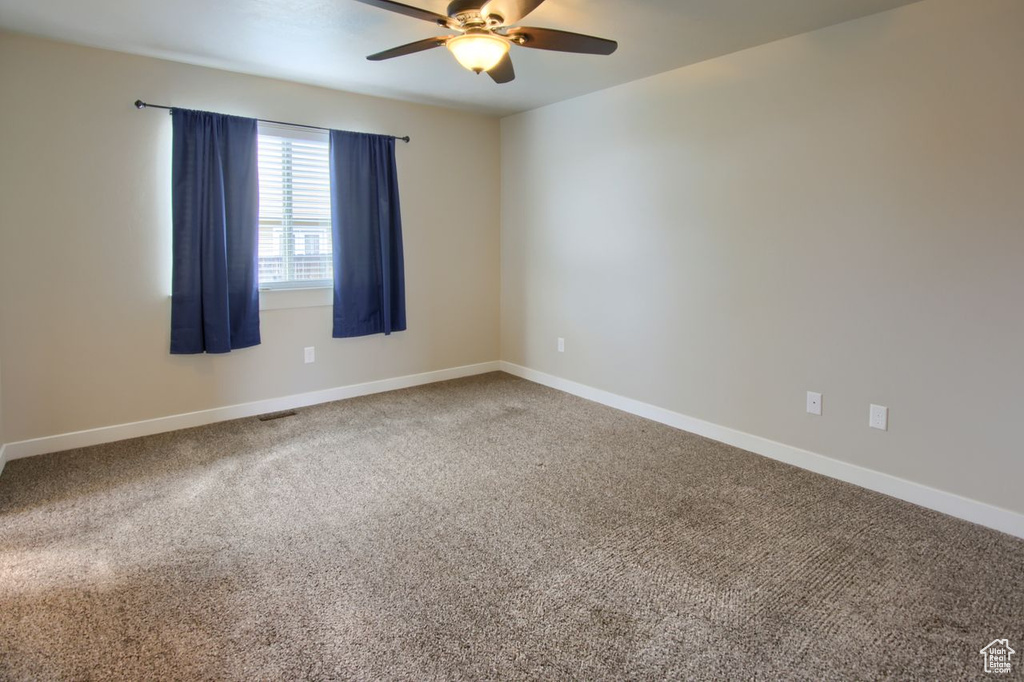 Spare room featuring baseboards, carpet, and ceiling fan